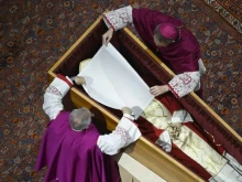 Before the wooden coffin is closed, Pope Benedict XVI’s personal secretary Archbishop Georg Gänswein and Monsignor Diego Giovanni Ravelli, the Vatican’s lead master of ceremonies for papal liturgies, place a white veil over the late pope’s face. The action on Jan. 4, 2023, is part of the funeral rites for popes.