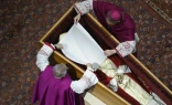 Before the wooden coffin is closed, Pope Benedict XVI’s personal secretary Archbishop Georg Gänswein and Monsignor Diego Giovanni Ravelli, the Vatican’s lead master of ceremonies for papal liturgies, place a white veil over the late pope’s face. The action on Jan. 4, 2023, is part of the funeral rites for popes.