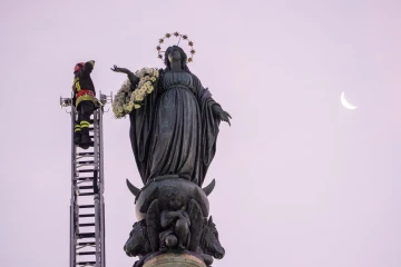 A firefighter in Rome pays tribute to the Blessed Virgin Mary by laying a wreath of fresh flowers at her statue atop a column near the Spanish Steps on Dec. 8, 2023.