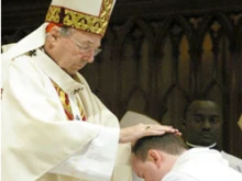 Cardinal George Pell ordains a man to the priesthood.