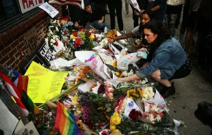 A girl places flowers at a vigil following the June 12, 2016 mass shooting a gay night club in Orlando.   Spencer Platt / Getty Images News.  