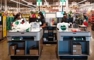 Cashiers ring up groceries for customers at the Local Market Foods store in Chicago, Illinois, on April 8, 2020.   KAMIL KRZACZYNSKI/AFP via Getty Images