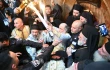 The Greek Orthodox Patriarch Theophilos III exits the Aedicule of the Holy Sepulcher on May 4, 2024, in Jerusalem, showing the faithful the two candles just lit from the oil lamp that is believed to have been miraculously ignited inside Jesus' tomb.