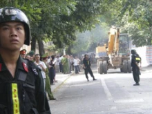 Vietnamese police stand guard as bulldozers work to demolish nunciature