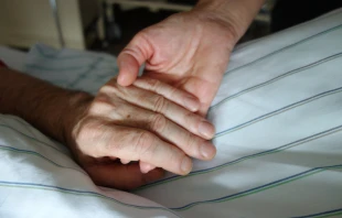 Nurse holding hand of patient. Stock photo via Shutterstock. 