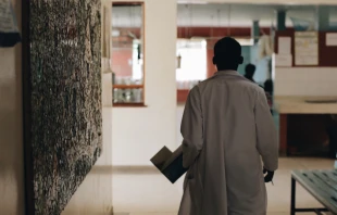 Doctor in white medical gown walking through the hospital lobby in village in Africa. Via Shutterstock 