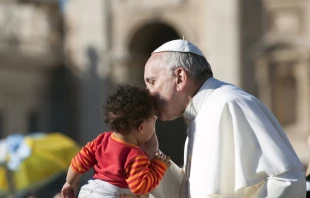 Pope Francis on the popemobile kiss child in St. Peter's Square.   Shutterstock