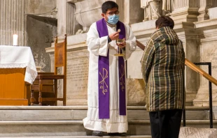 Priest distributes communion at the church of Santa Maria in Trastevere, Rome.   Pino Mastrullo/Shutterstock