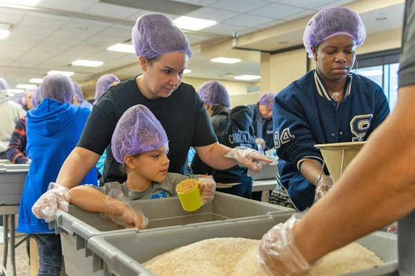 Volunteers fill cups and bags with rice, vitamin-fortified crushed soy, a vitamin blend, and dehydrated vegetables at packaging stations set up in the St. Isidore social hall. The organized effort will allow those who receive the meals to simply add six cups of water to feed up to six adults or 12 children. Credit: Steven Stechschulte/Special to Detroit Catholic