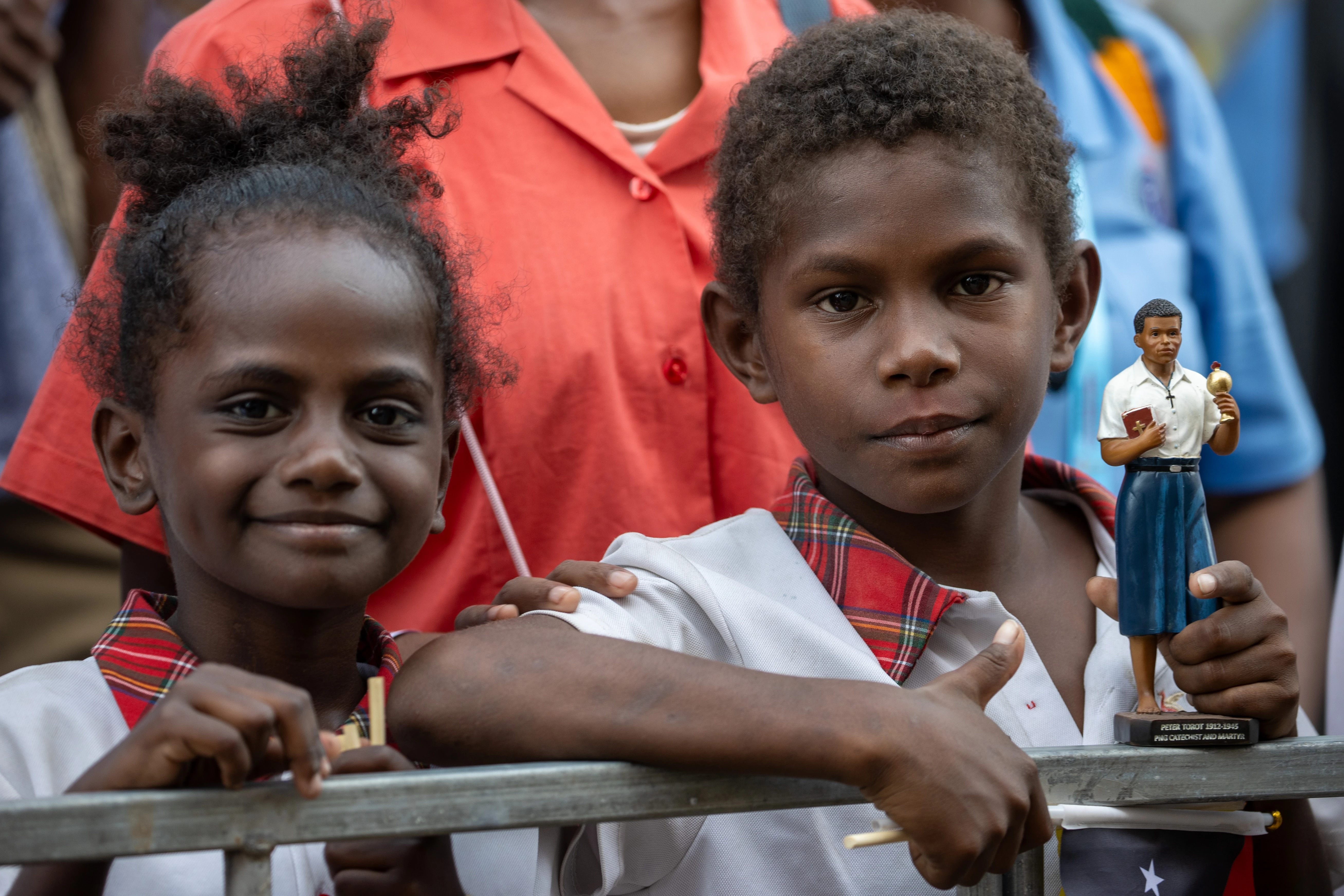 Two children, one of them holding a statue of Blessed Peter To Rot, await the visit of Pope Francis at the Caritas Technical Secondary School in Port Moresby, Papua New Guinea, Sept. 7, 2024.?w=200&h=150