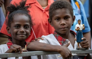 Two children, one of them holding a statue of Blessed Peter To Rot, await the visit of Pope Francis at the Caritas Technical Secondary School in Port Moresby, Papua New Guinea, Sept. 7, 2024. Credit: Daniel Ibáñez/CNA