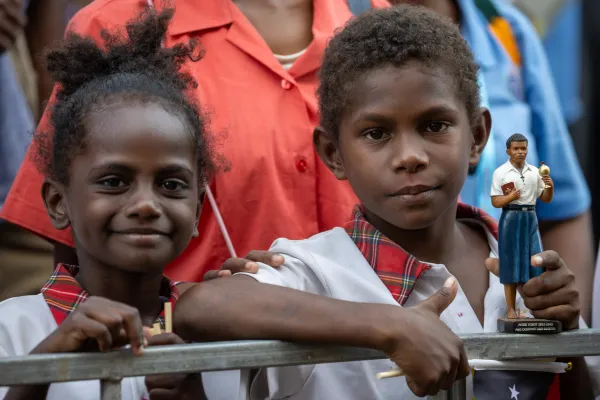 Two children, one of them holding a statue of Blessed Peter To Rot, await the visit of Pope Francis at the Caritas Technical Secondary School in Port Moresby, Papua New Guinea, Sept. 7, 2024. Credit: Daniel Ibáñez/CNA