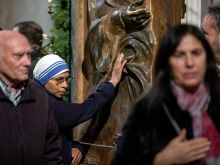 A Sister of the Missionaries of Charity touches the bronze Holy Door at the papal basilica during its opening for the 2025 Jubilee Year. The religious sister, wearing the distinctive white and blue habit of the order founded by Mother Teresa, joins other faithful in this traditional gesture of devotion as they pass through the ceremonial door on Jan. 1, 2025.