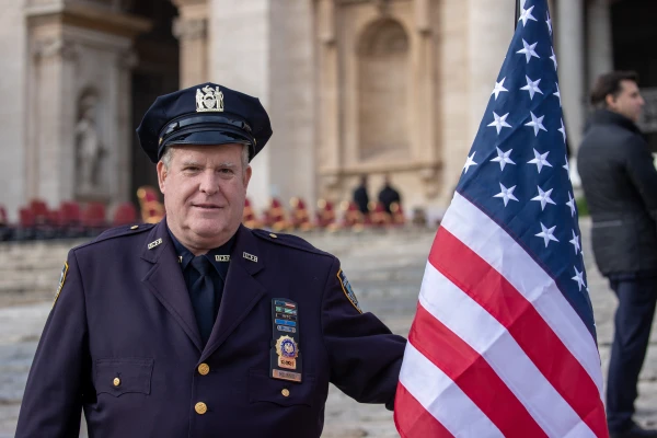 A New York City police officer holds an American flag during the Armed Forces Jubilee Mass in St. Peter's Square on Feb. 9, 2025. | Daniel Ibáñez/CNA. Credit: Daniel Ibáñez/CNA