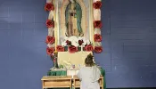 A migrant woman prays in front of an image of Our Lady of Guadalupe at a migrant shelter in McAllen, Texas, run by Catholic Charities of the Rio Grande Valley.