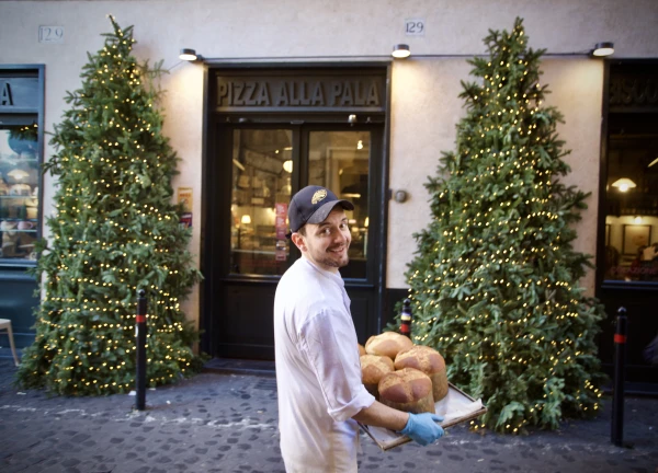 A baker is seen carrying a tray of panettone in Rome, Italy, Dec. 17, 2024. Credit: Courtney Mares/CNA