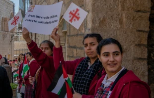 Children welcome the custos of the Holy Land, Father Francesco Patton, upon his entrance into Bethlehem on Nov. 30, 2024, for the beginning of Advent. The custos’ entry was festive, but at the same time, it was impossible to ignore the echoes of war. The children were holding signs with messages of peace and solidarity for those suffering due to the war. Credit: Marinella Bandini