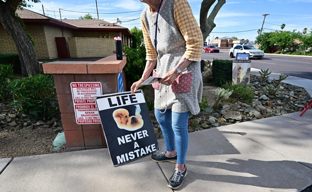 Longtime pro-life advocate Lynn Dyer places a sign that reads “Life Never a Mistake” on public property in front of Camelback Family Planning, an abortion clinic in Phoenix, on April 18, 2024.?w=200&h=150