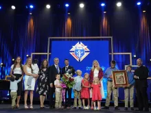 Joe and Tiffany Ampe, with 11 of their 13 children, accept the International Family of the Year award from Supreme Knight Patrick E. Kelly at an awards session prior to the 142nd Supreme Convention in Québec City on Aug. 5, 2024. Joe Ampe, a Knight from Marquette, Michigan, and his family were recognized for their service to their parish and their community, particularly their efforts to deliver humanitarian aid to Ukraine, the home country of three of their adopted children.