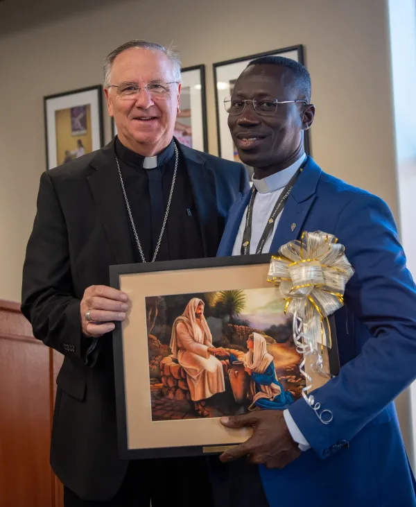 Bishop John Dolan of the Diocese of Phoenix presents a “Woman of the Well” painting by Glenda Stevens to Father Israel Boadi. Dolan is the chaplain of the Association of Catholic Mental Health Ministers. Credit: Brett Meister/Diocese of Phoenix