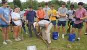 Ben Kresse, a theology teacher at St. Xavier High School, shows a group of students how to uncover a temporary marker on a gravesite in Meadow View Cemetery, Louisville, Kentucky, Sept. 21, 2024.