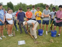 Ben Kresse, a theology teacher at St. Xavier High School, shows a group of students how to uncover a temporary marker on a gravesite in Meadow View Cemetery, Louisville, Kentucky, Sept. 21, 2024.