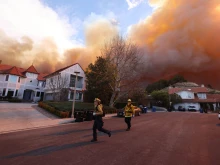 Firefighters run as a brush fire burns in Pacific Palisades, California, on Jan. 7, 2025. A fast-moving brushfire in a Los Angeles suburb burned buildings and sparked evacuations as “life-threatening” winds whipped the region.