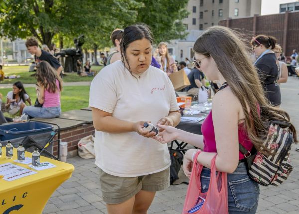 Anna Picasso, left, outreach coordinator for Detroit Catholic Campus Ministry, offers a bottle of holy water to a student at the College for Creative Studies in Detroit on Aug. 26, 2024. Picasso said the campus ministry team explains to students the purpose of holy water, inviting students to bless their dorms, apartments, cars, and study spaces. Credit: Valaurian Waller/Detroit Catholic