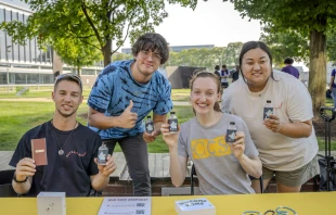 Left to right, Victor Fenik, J.P. Ledermann, Jocelyn Reiter, and Anna Picasso distribute bottles of holy water to new and returning students during the involvement fair on Aug. 26, 2024, at the College for Creative Studies in Detroit. Members of Detroit Catholic Campus Ministry have been distributing holy water at the start of the academic year at local colleges and universities for the past three years. Credit: Valaurian Waller/Detroit Catholic