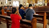 Catholic men and women kneel down and pray inside the Antipolo Cathedral in the Philippines.
