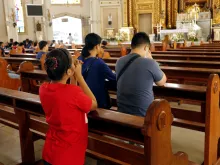 Catholic men and women kneel down and pray inside the Antipolo Cathedral in the Philippines.