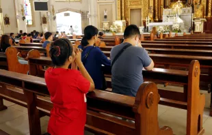 Catholic men and women kneel down and pray inside the Antipolo Cathedral in the Philippines. Credit: junpinzon/Shutterstock