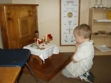 A child prays before the altar area in a Catechesis of the Good Shepherd atrium.