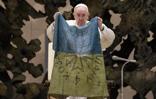 Pope Francis holds a flag that he received from Bucha, Ukraine at his general audience on April 6, 2022. Vatican Media