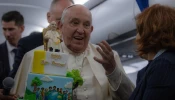 Pope Francis is presented with a birthday cake aboard the papal plane on the return from his trip to Corsica on Sunday, Dec. 15, 2024.