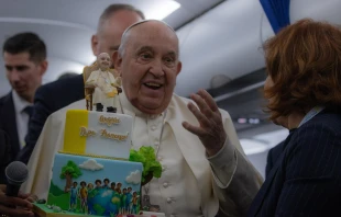 Pope Francis is presented with a birthday cake aboard the papal plane on the return from his trip to Corsica on Sunday, Dec. 15, 2024. Credit: Daniel Ibáñez/CNA