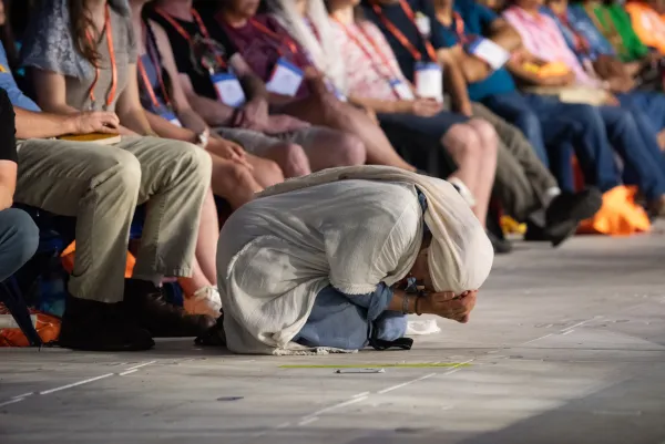 A woman at the National Eucharistic Congress kneels in prayer. Credit: Jeffrey Bruno