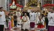 Pope Francis carries the statue of the Child Jesus to place in the Nativity scene inside St. Peter's Basilica at the end of Mass on Christmas Eve, Dec. 24, 2024, surrounded by children dressed in traditional clothing from their countries.