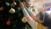 A young girl hangs an ornament on the Christmas tree inside the Church of the Holy Family in Gaza.