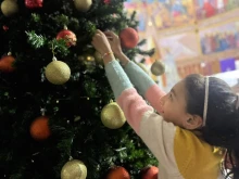 A young girl hangs an ornament on the Christmas tree inside the Church of the Holy Family in Gaza.