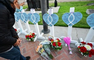 A woman takes a closer look at the names of 11 people killed in a mass shooting written on crosses and displayed during a candlelight vigil in front of the City Hall in Monterey Park, California, on Jan. 24, 2023. Photo by FREDERIC J. BROWN/AFP via Getty Images