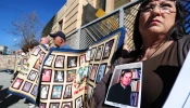 Esther Miller holds a picture and the released documents on Father Michael Nocita as victims and their supporters hold quilts bearing portraits of abused children while gathered outside the Cathedral of Our Lady of the Angels in Los Angeles on Feb. 1, 2013.