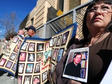 Esther Miller holds a picture and the released documents on Father Michael Nocita as victims and their supporters hold quilts bearing portraits of abused children while gathered outside the Cathedral of Our Lady of the Angels in Los Angeles on Feb. 1, 2013.