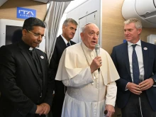 Pope Francis addresses journalists aboard the papal plane heading to Mongolia, with Cardinal-elect George Jacob Koovakad at left, on Aug. 31, 2023.