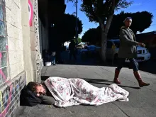A homeless man sleeps on the sidewalk in downtown Los Angeles on Nov. 22, 2023.