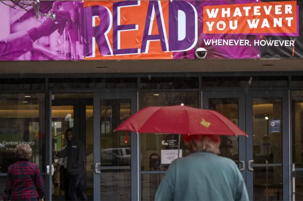 People pass beneath a huge banner supporting banned books at the Arlington Library in Arlington, Virginia. Credit: Bill O'Leary/The Washington Post via Getty Images