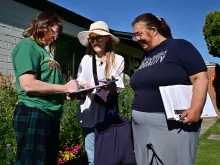 Volunteer canvassers Liz Grumbach (center) and Patricia Jones meet Lucy Meyer (left), who signs a petition outside her home in Phoenix on April 13, 2024, as the volunteers go door-to-door for signatures to get the petition for the Arizona Abortion Access Act onto the November 2024 ballot for voters to decide.