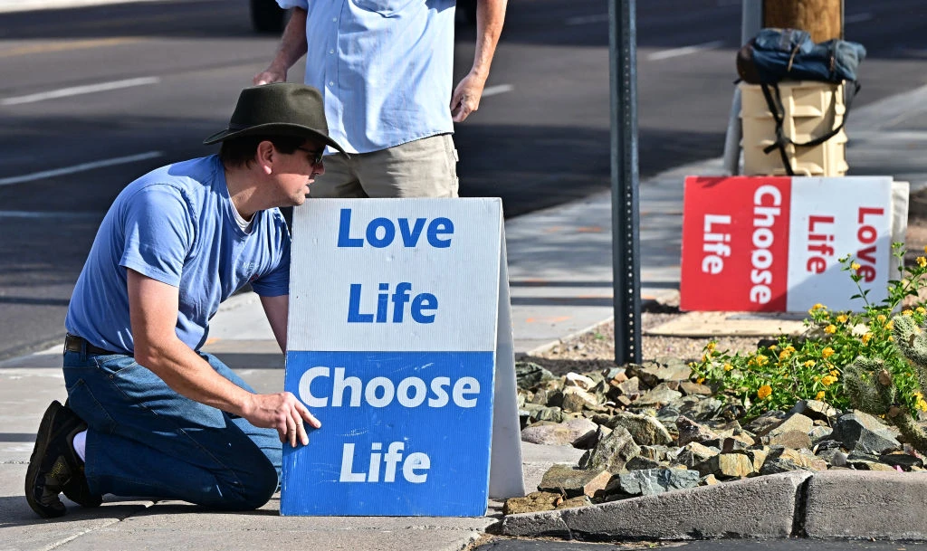 Pro-life activist Matthew Engelthaler places signs in front of Camelback Family Planning, an abortion clinic in Phoenix, on April 18, 2024.?w=200&h=150