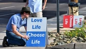 Pro-life activist Matthew Engelthaler places signs in front of Camelback Family Planning, an abortion clinic in Phoenix, on April 18, 2024.