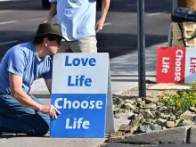 Pro-life activist Matthew Engelthaler places signs in front of Camelback Family Planning, an abortion clinic in Phoenix, on April 18, 2024.